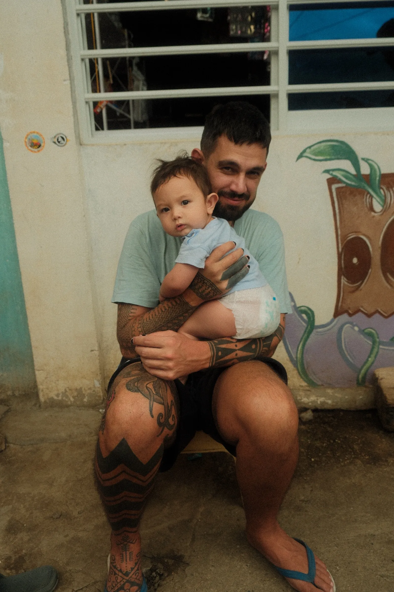 Teo holding his three-month-old son outside the house in Buscalan.
